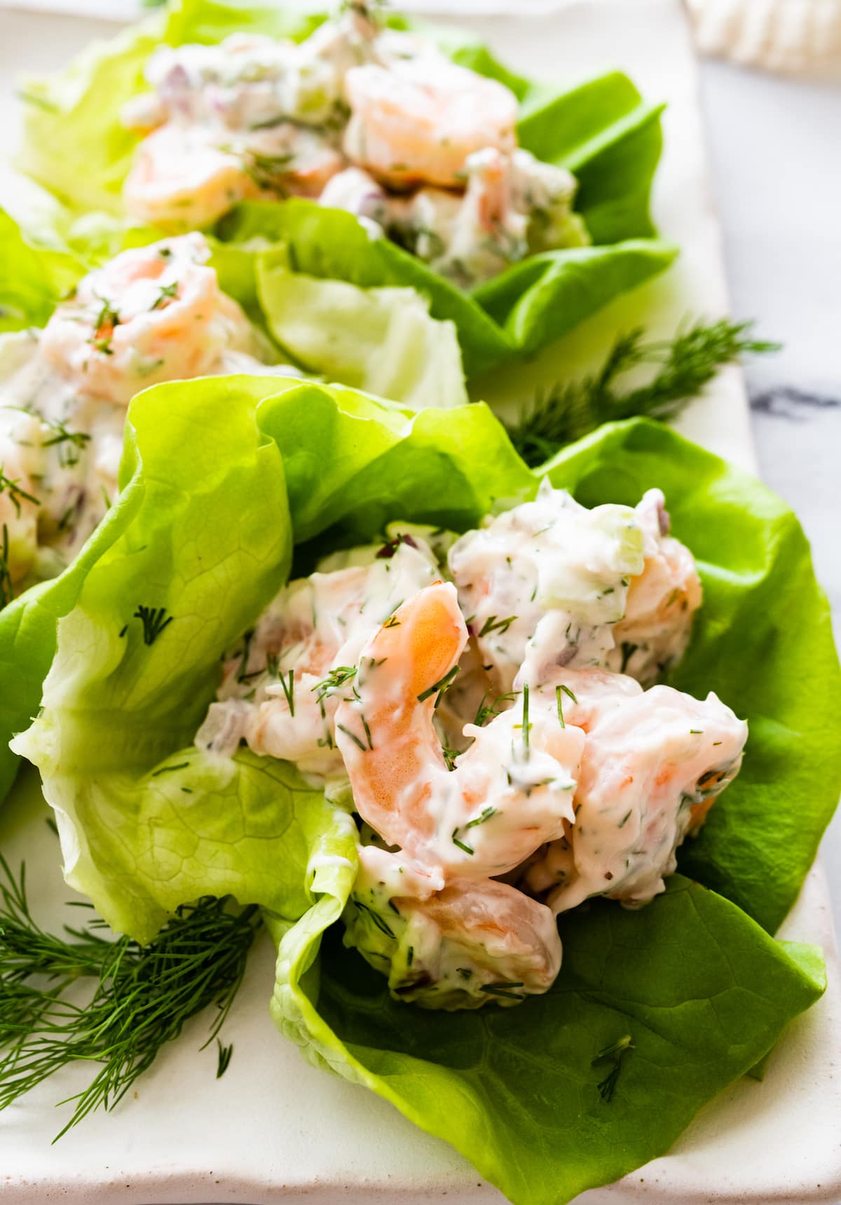 Shrimp salad in lettuce wraps served on a white platter.