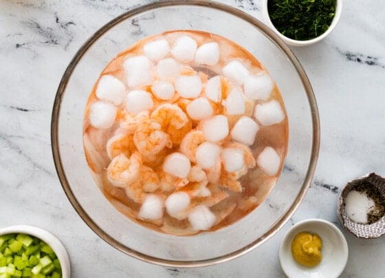 Cooked shrimp cooling off in a bowl with ice water.