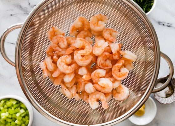 Cooked shrimp in a strainer.