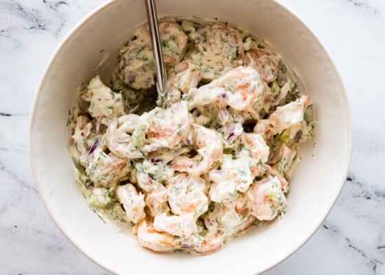 Shrimp salad ingredients all mixed together in a white mixing bowl.