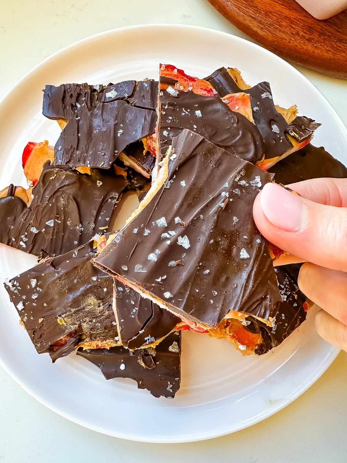 Woman holding a piece of chocolate peanut butter strawberry bark.