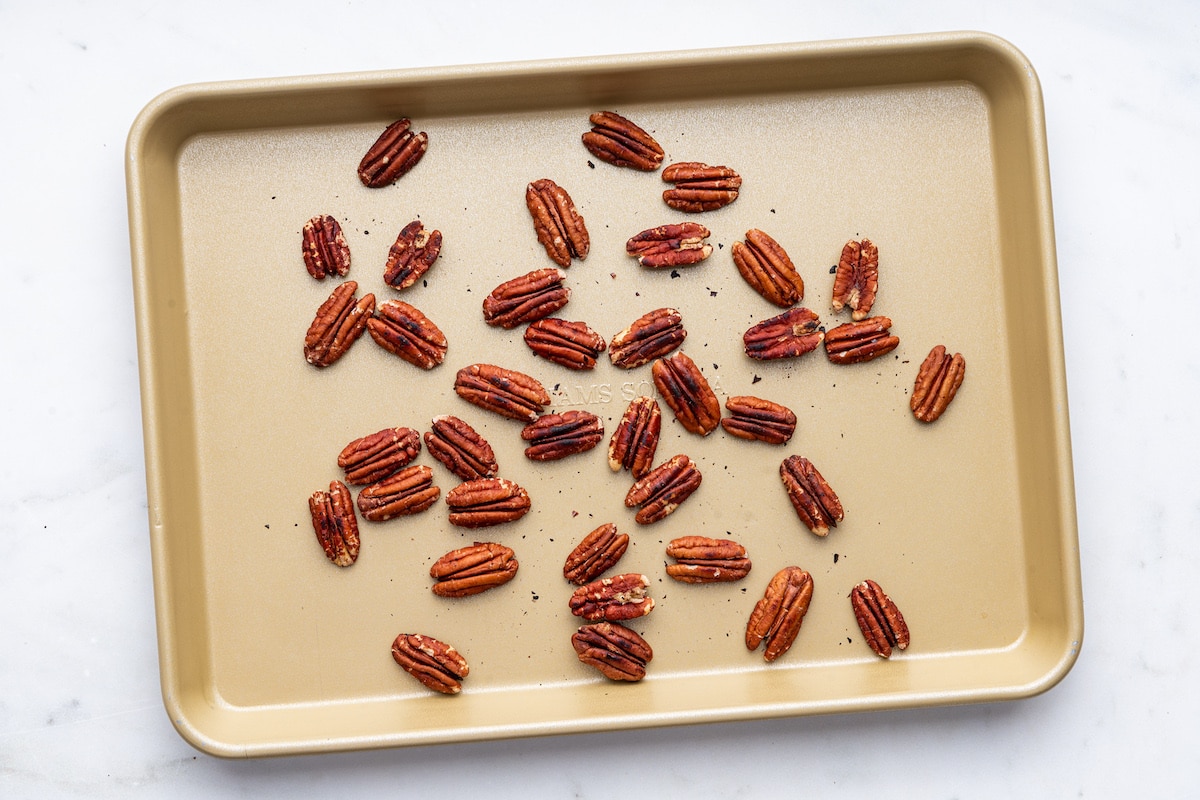 Roasted pecans on a baking sheet for the strawberry spinach salad.