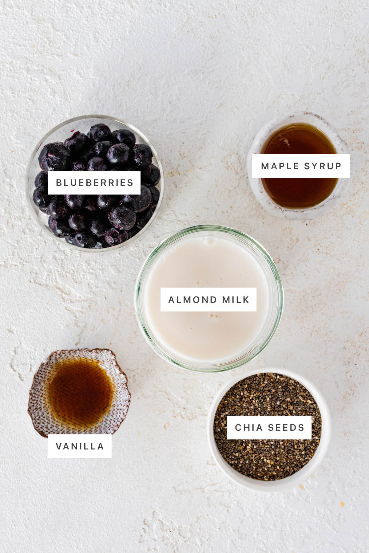 Ingredients measured out to make Blueberry Chia Pudding: blueberries, maple syrup, almond milk, vanilla and chia seeds.