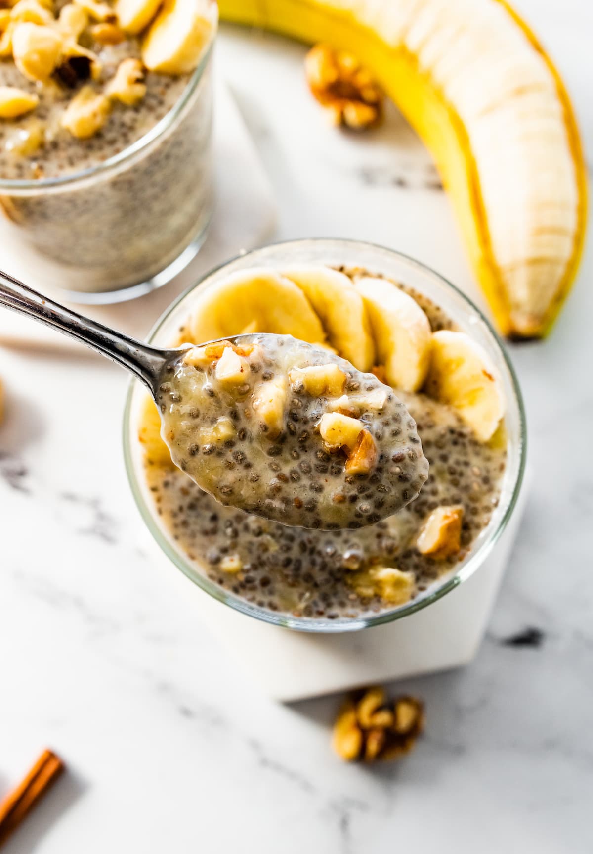 A spoonful of banana chia pudding over a glass of the pudding.