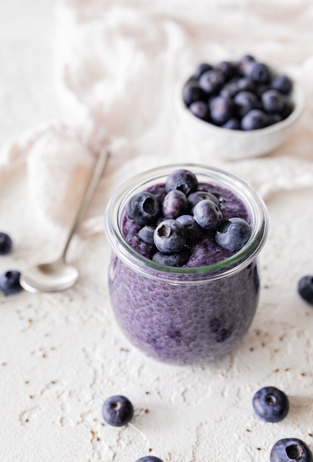 Blueberry chia pudding in a glass cup topped with fresh blueberries.