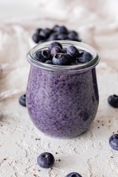 Blueberry chia pudding in a glass cup topped with fresh blueberries.