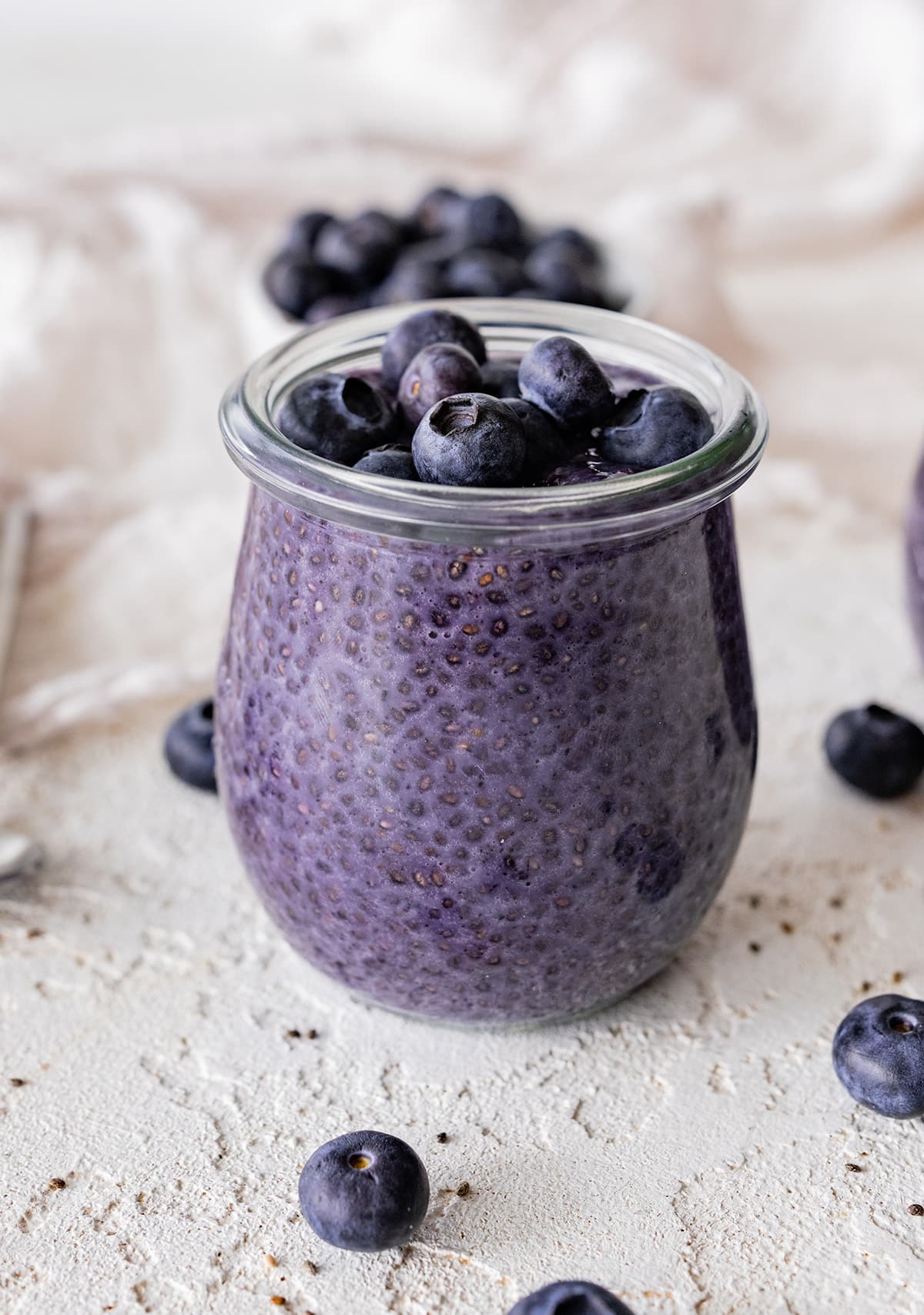 Blueberry chia pudding in a glass cup topped with fresh blueberries.