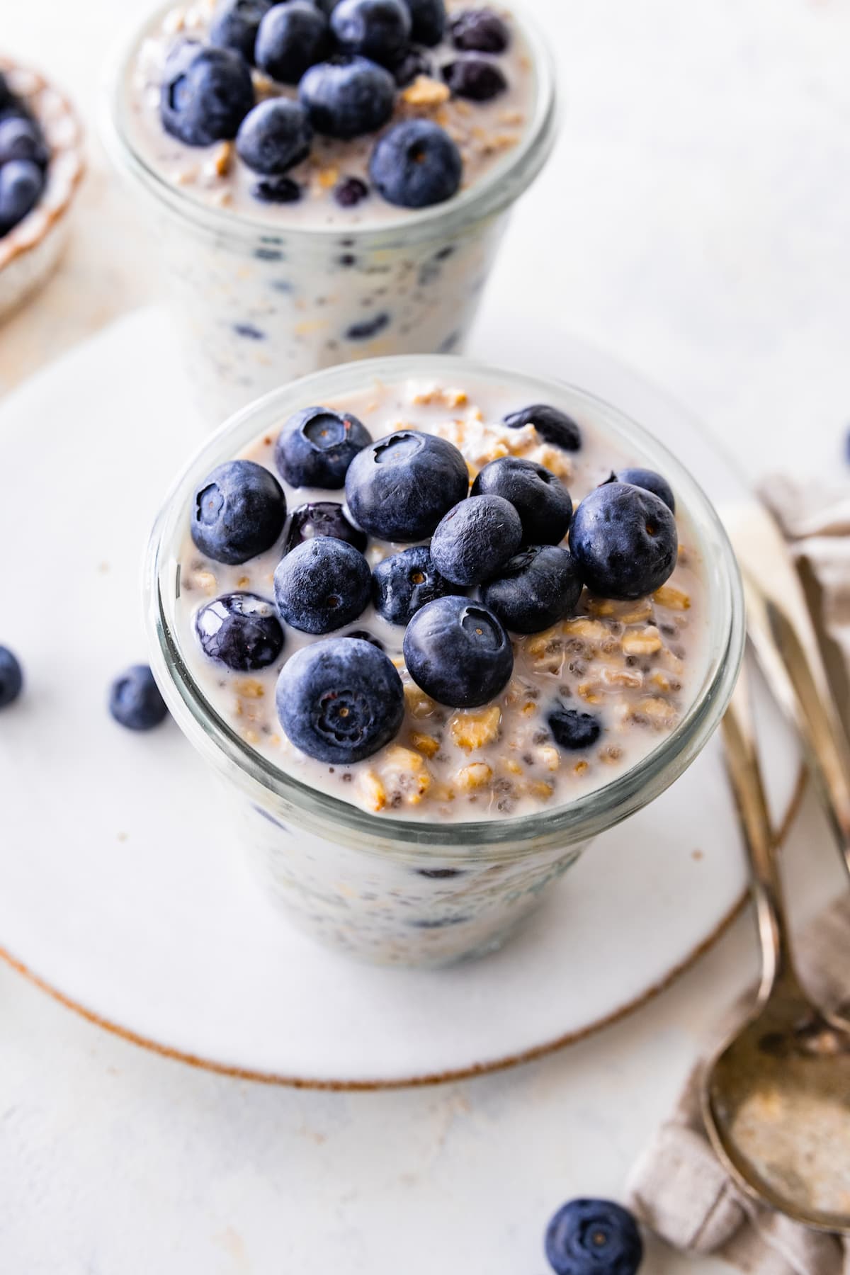 Two glasses of blueberry overnight oats topped with fresh blueberries.