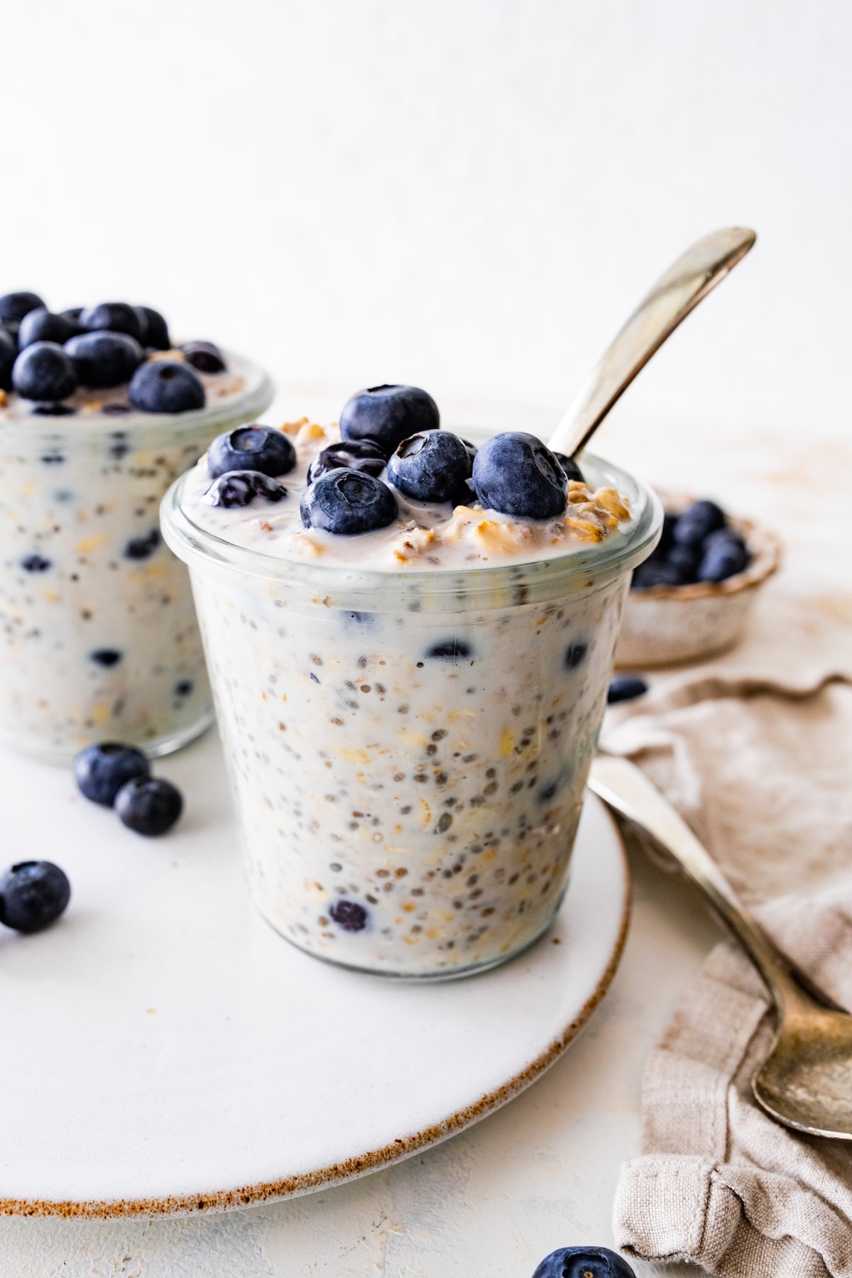 Two glasses of blueberry overnight oats topped with fresh blueberries.