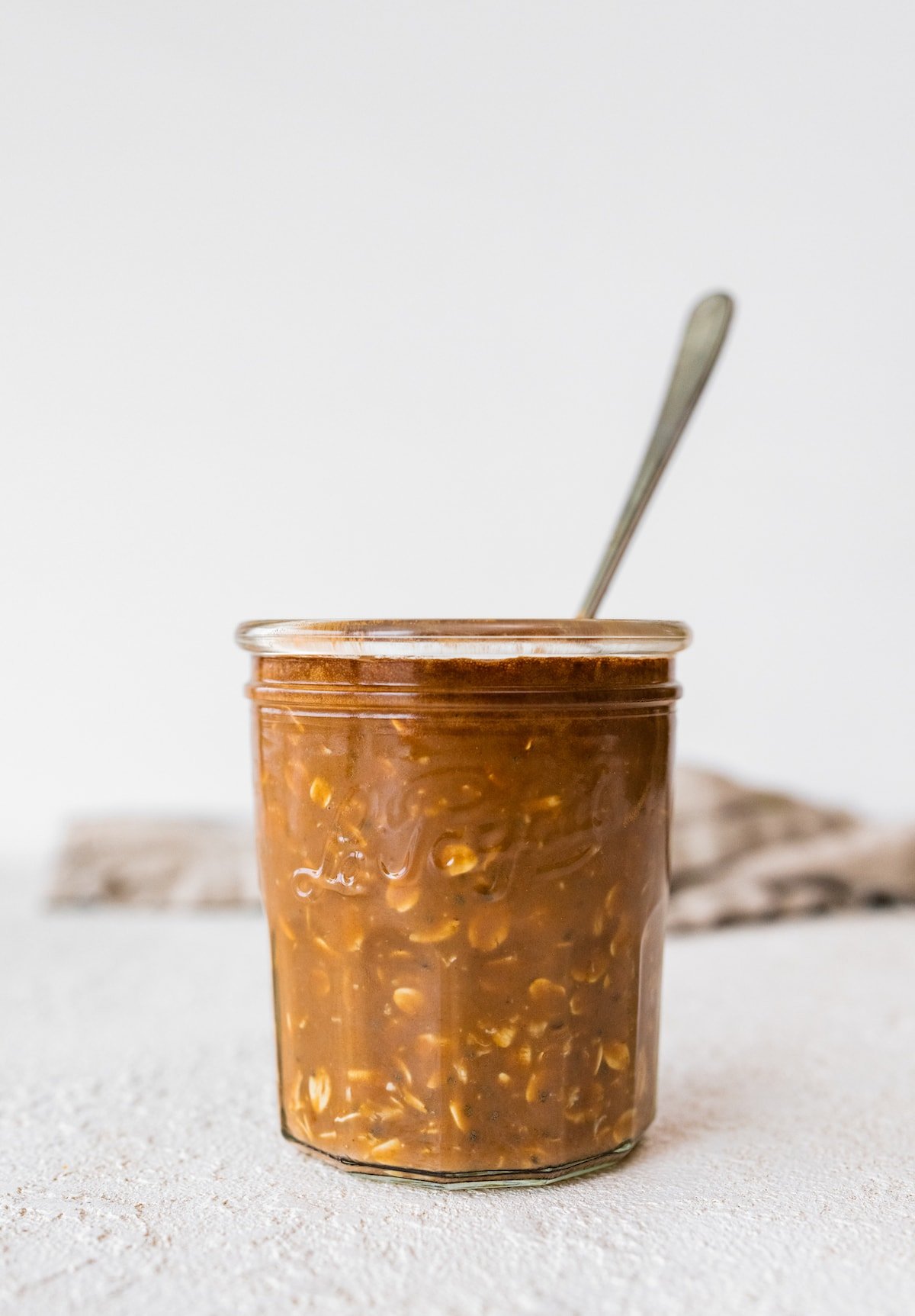 A jar of the mixed chocolate overnight oats with a spoon.