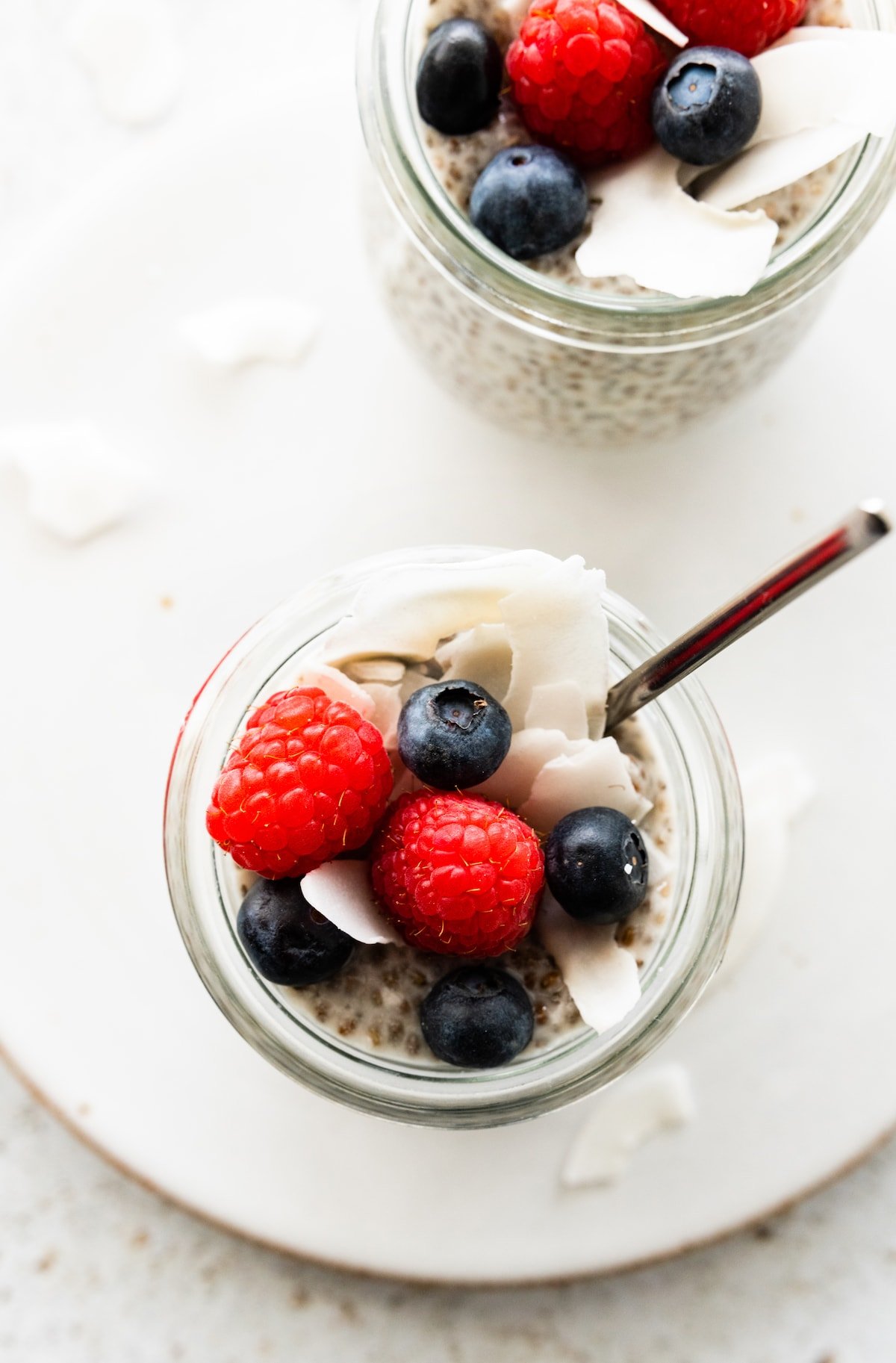 Coconut chia pudding in a glass cup, topped with fresh berries.