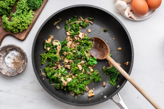 The sautéed onion, kale and mushrooms in a skillet for the crustless quiche.