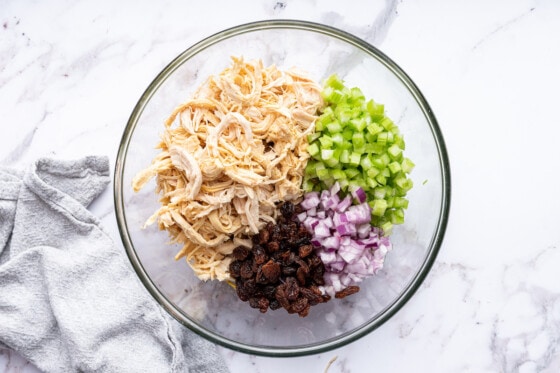 Ingredients for the curry chicken salad in a large glass bowl.