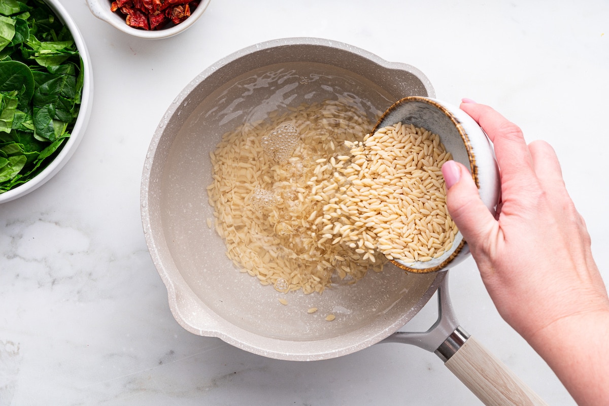 Orzo being poured into a pot of water.
