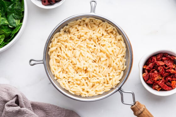 Cooked orzo in a strainer.