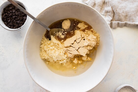 The protein cookie dough bark ingredients being mixed together in a bowl.