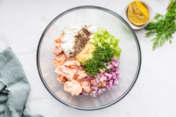 Ingredients for the salmon salad in a glass bowl before being mixed.