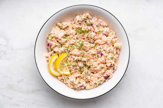 Salmon salad in a bowl with two lemon slices.