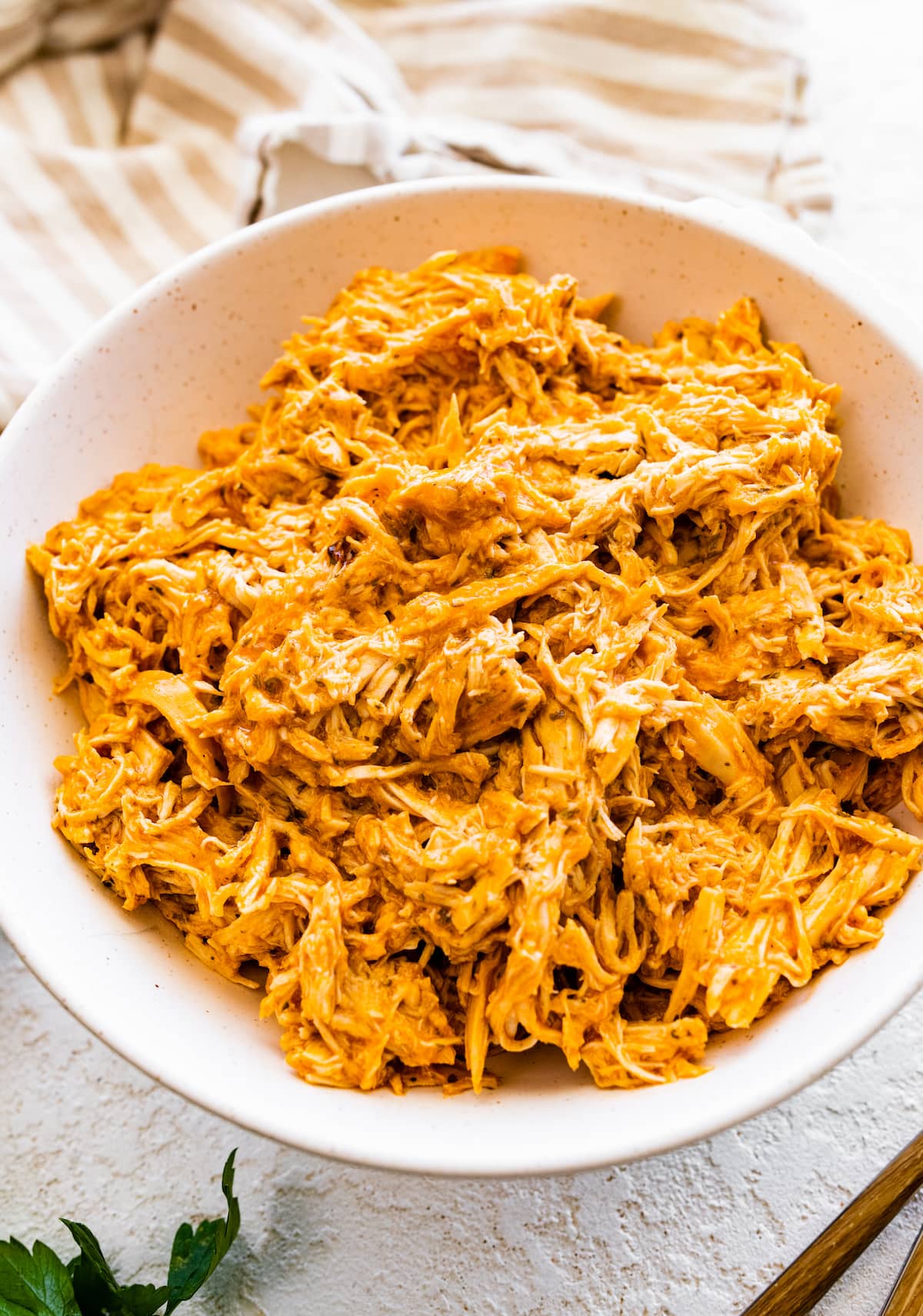 Slow cooked shredded buffalo chicken in a bowl.
