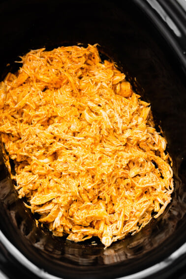 Shredded buffalo chicken in a slow cooker.