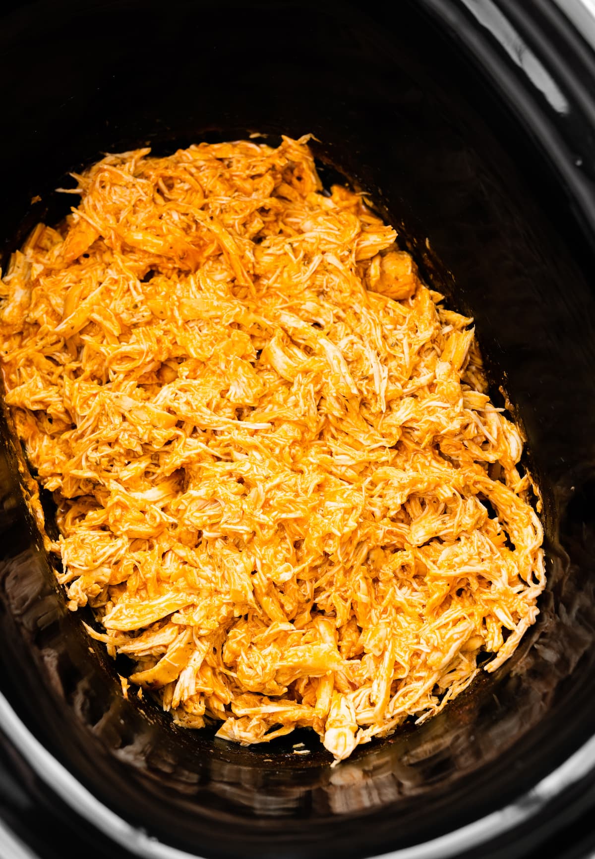 Shredded buffalo chicken in a slow cooker.