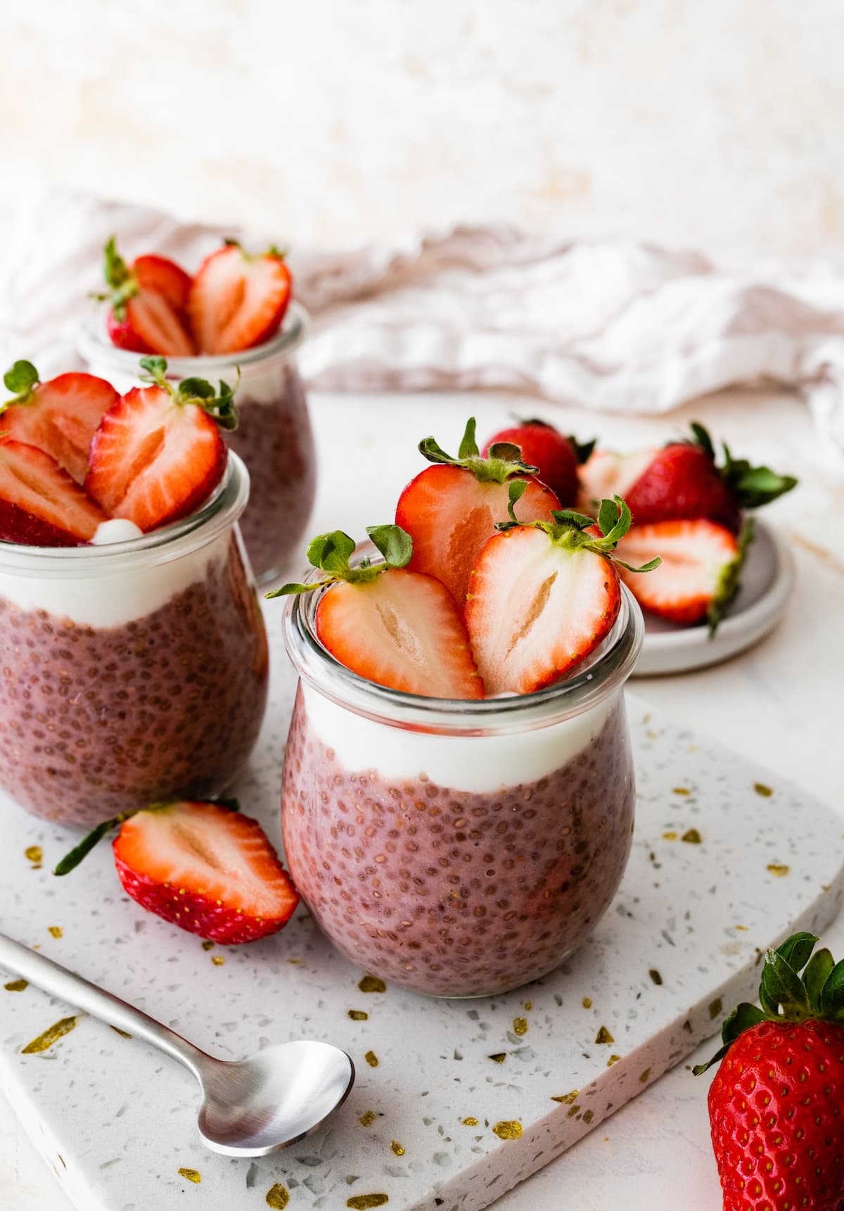 Two glass cups of strawberry chia pudding topped with fresh strawberries.
