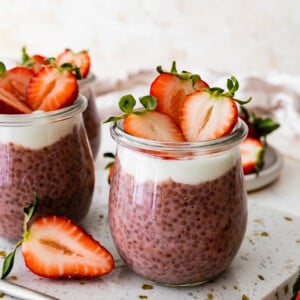 Two glass cups of strawberry chia pudding topped with fresh strawberries.