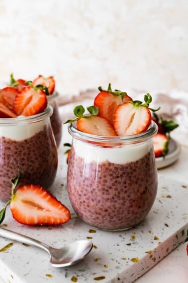 Two glass cups of strawberry chia pudding topped with fresh strawberries.