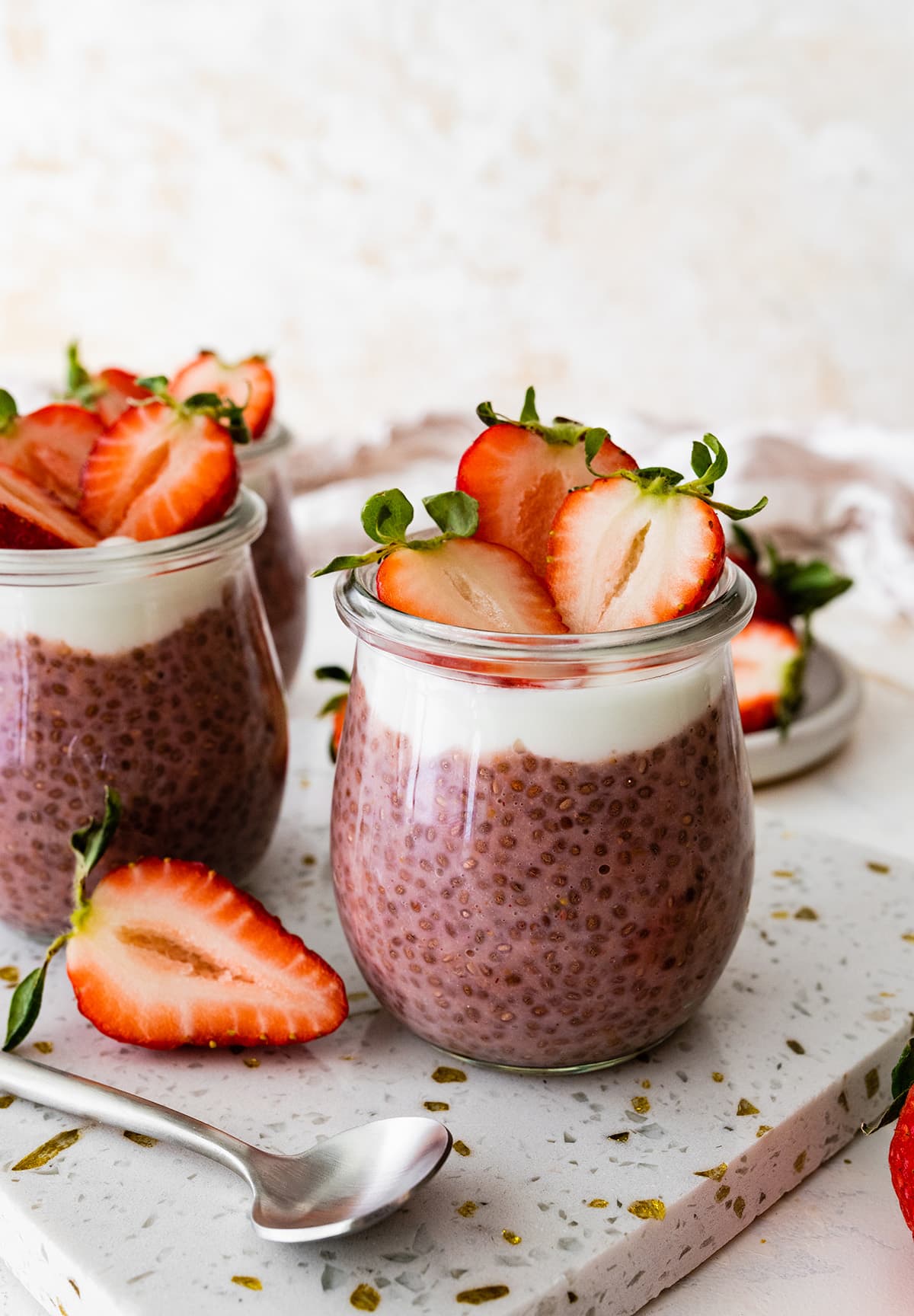 Two glass cups of strawberry chia pudding topped with fresh strawberries.