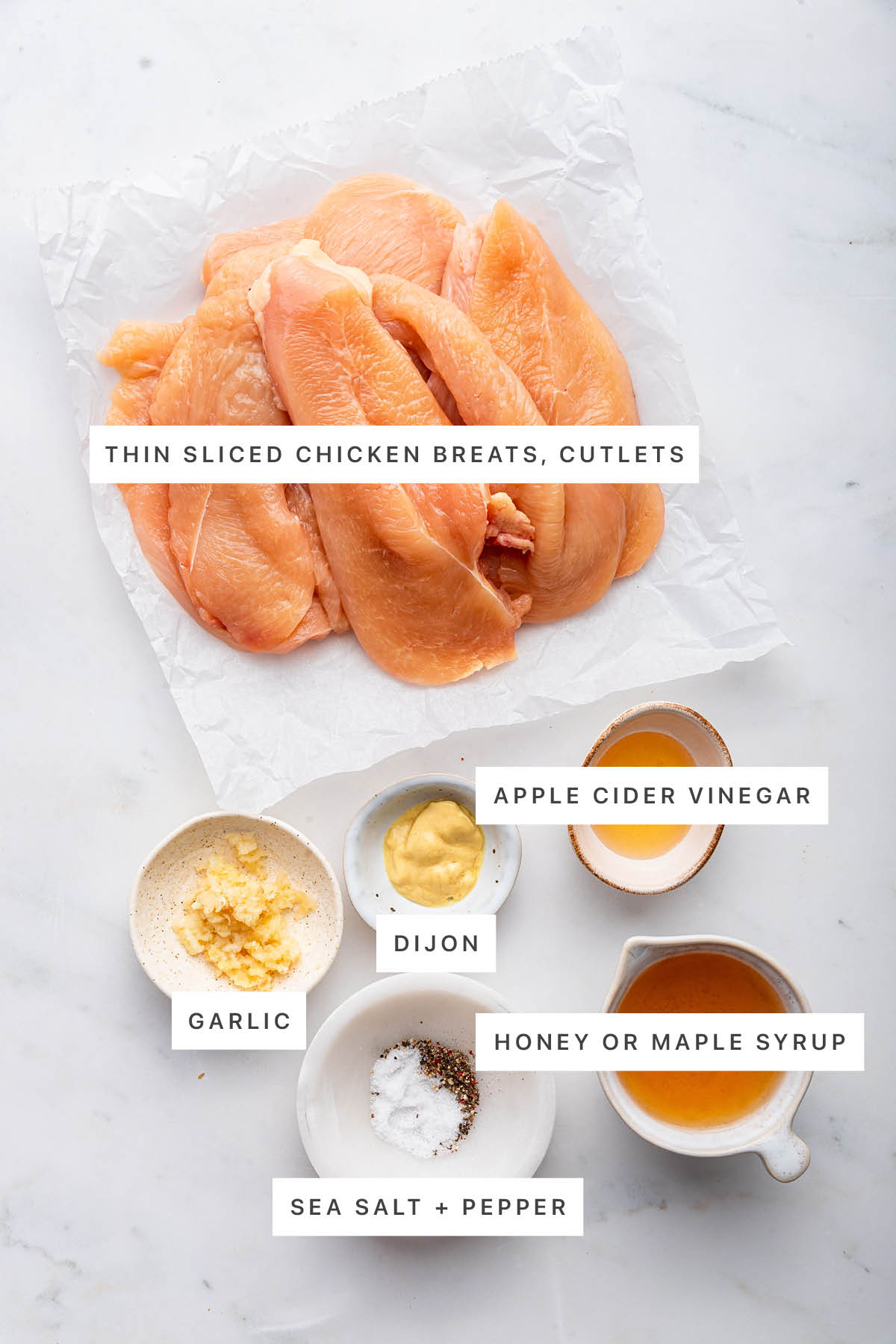 Ingredients measured out to make Air Fryer Chicken Cutlets: chicken cutlets, garlic, dijon, apple cider vinegar, sea salt, pepper and honey.