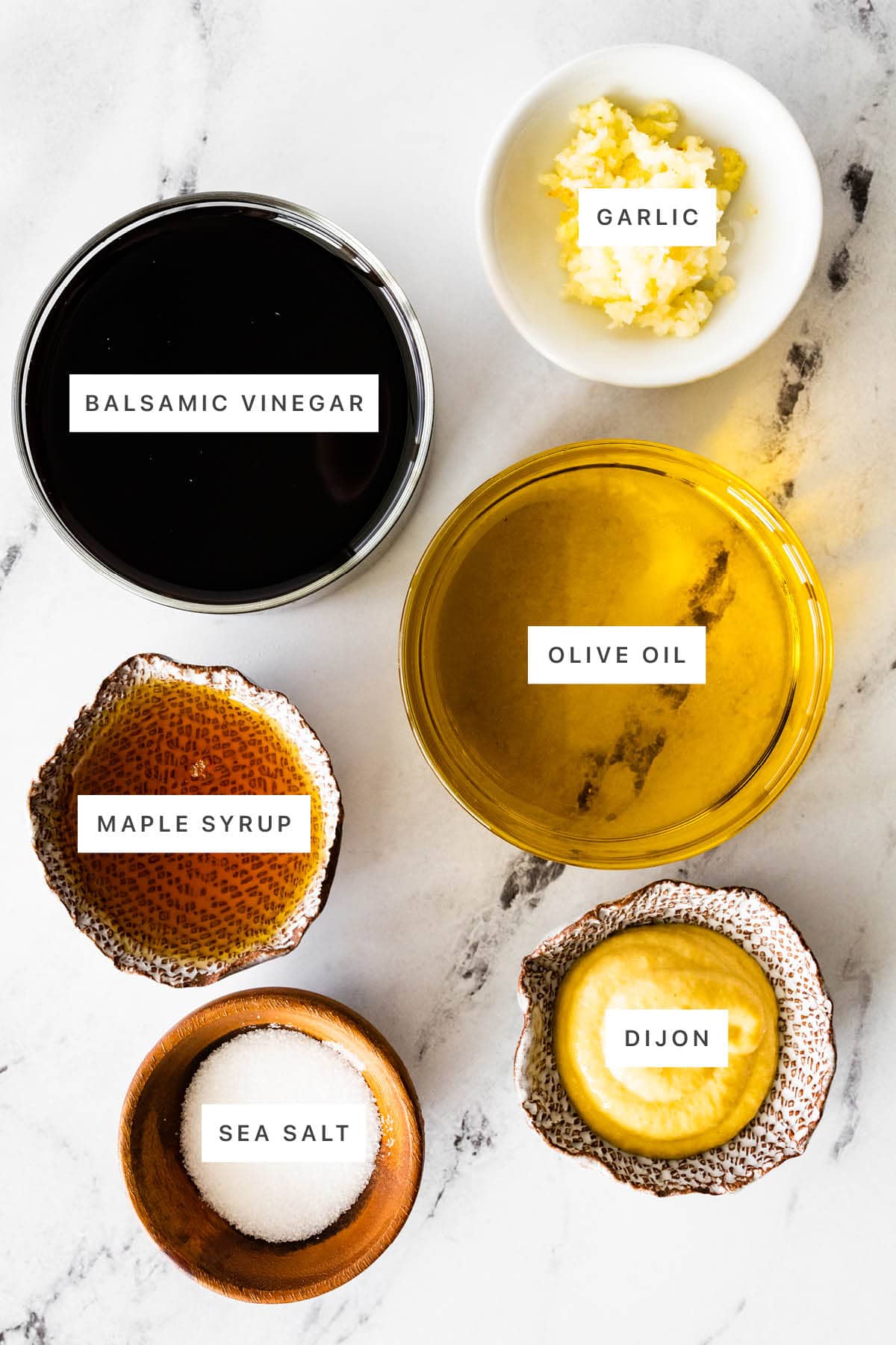 Ingredients measured out to make Balsamic Vinaigrette: balsamic vinegar, garlic, maple syrup, olive oil, sea salt and dijon.