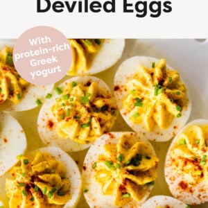 Deviled eggs on a plate garnished with chives and paprika.