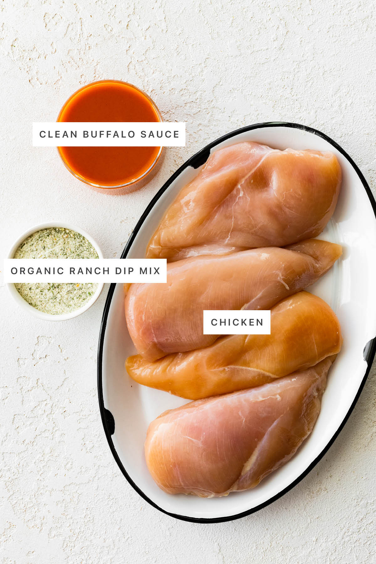 Ingredients measured out to make Slow Cooker Buffalo Chicken: clean buffalo sauce, organic ranch dip mix and chicken.