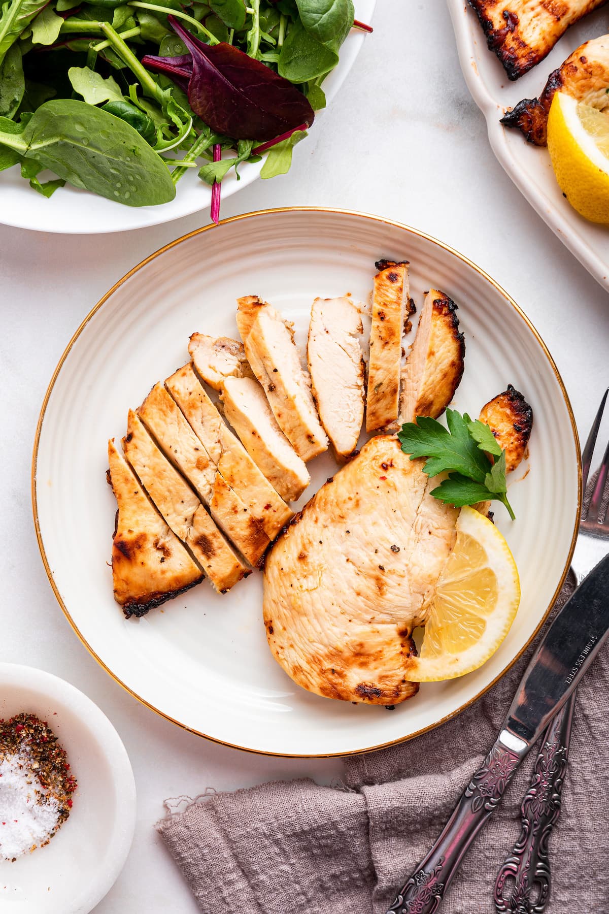 Two cooked chicken cutlets being served on a plate. One of the cutlets is sliced.