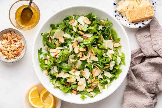 Arugula salad topped with sliced almonds and shaved parmesan cheese.