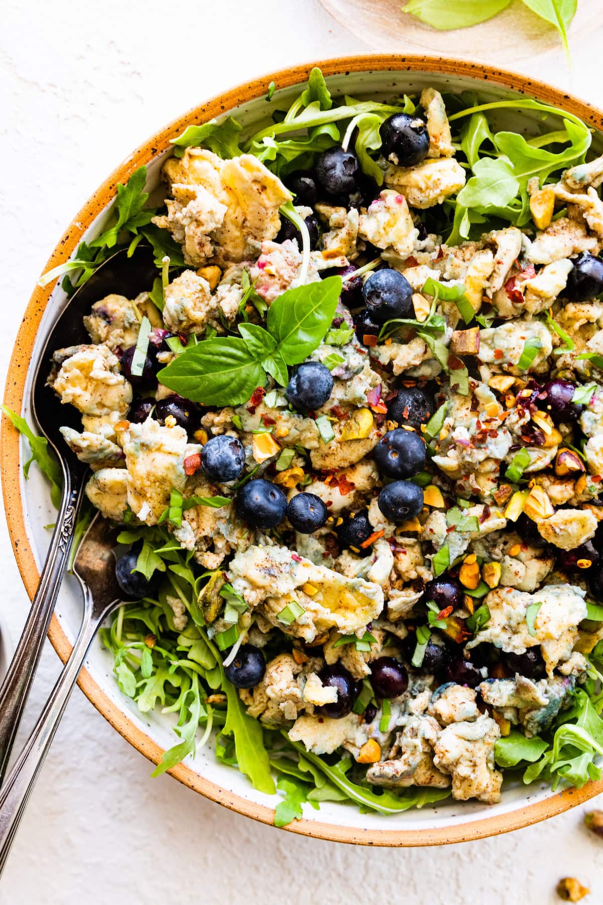 A blueberry breakfast salad with eggs and fresh greens in a bowl.