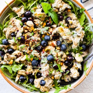 A blueberry breakfast salad with eggs and fresh greens in a bowl.