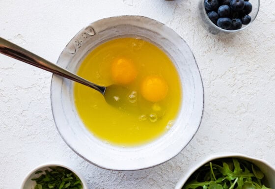 Two raw eggs in a bowl with a fork.