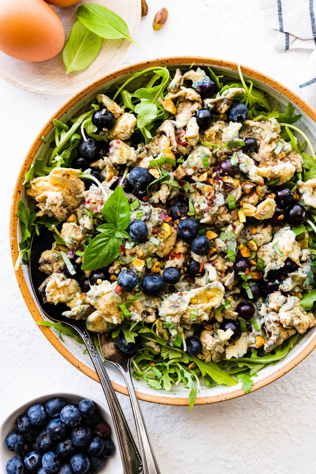 A blueberry breakfast salad with eggs and fresh greens in a bowl.