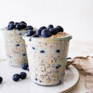 Two glasses of blueberry overnight oats topped with fresh blueberries.