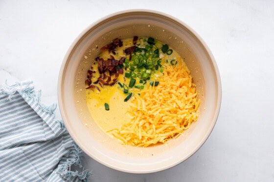 Cheese, egg, bacon, and green onion in a large mixing bowl.