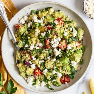 Bowl of quinoa salad with feta, spinach and tomatoes.