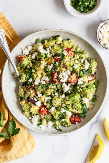 Bowl of quinoa salad with feta, spinach and tomatoes.