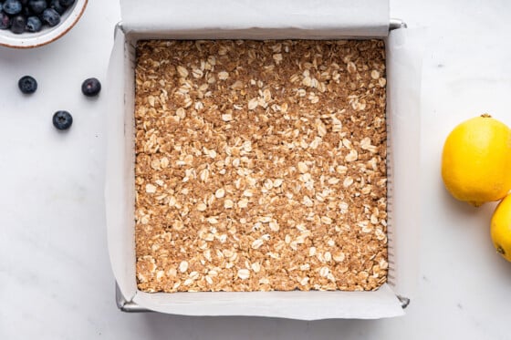 One layer of blueberry crumble bar in a square baking pan.