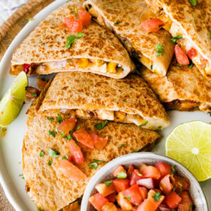 Healthy chicken quesadilla on a plate with a side bowl of pico de gallo.