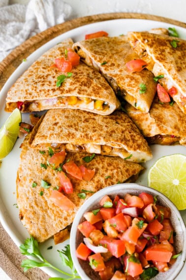 Healthy chicken quesadilla on a plate with a side bowl of pico de gallo.