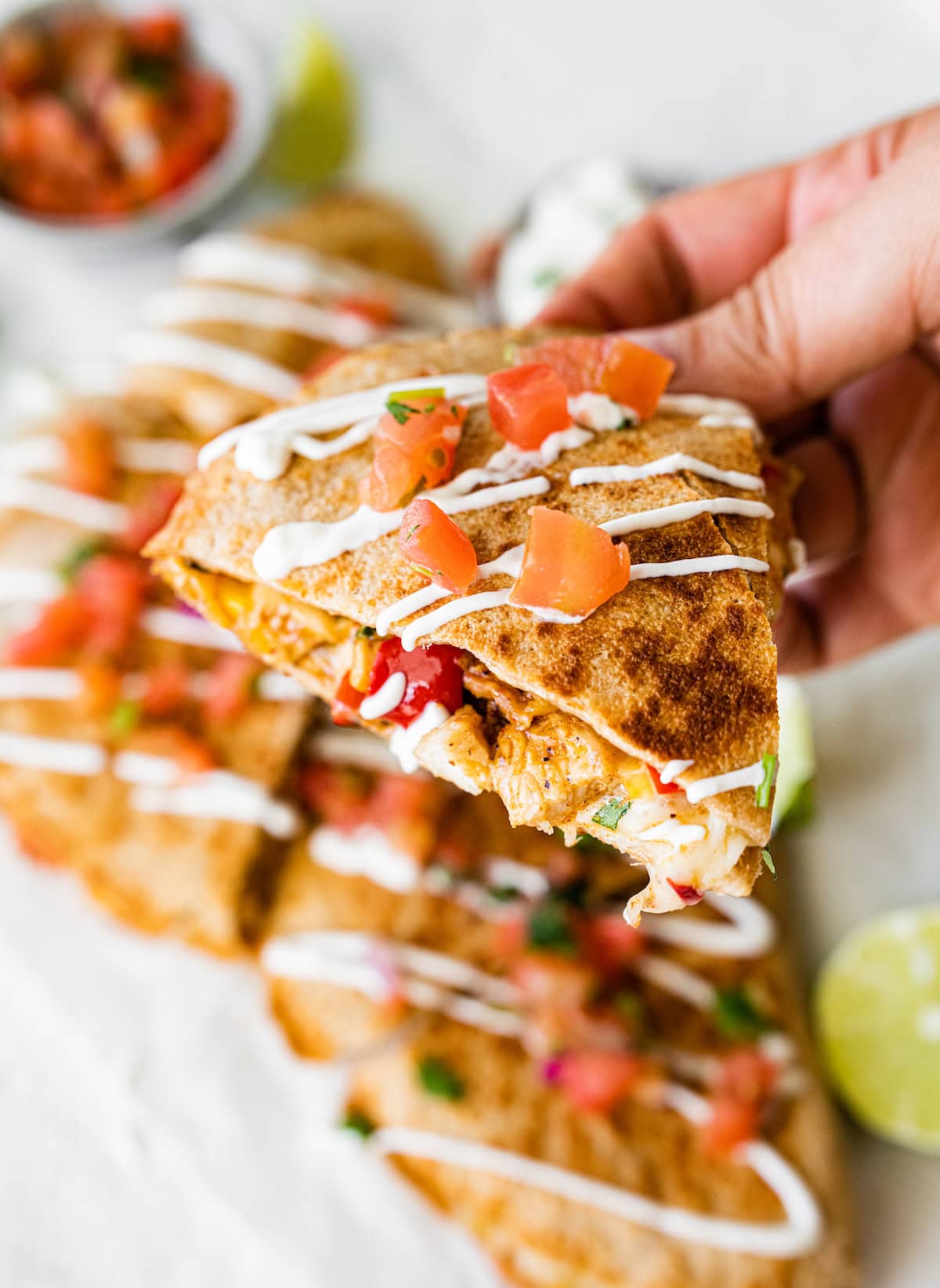 A hand holding a piece of a chicken quesadilla.