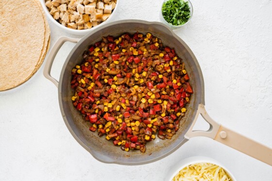 Cooked corn, onion, and tomato in a large skillet.