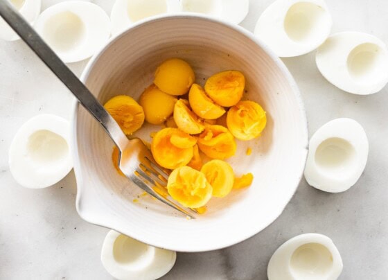 Cooked egg yolks in a large bowl with a fork.