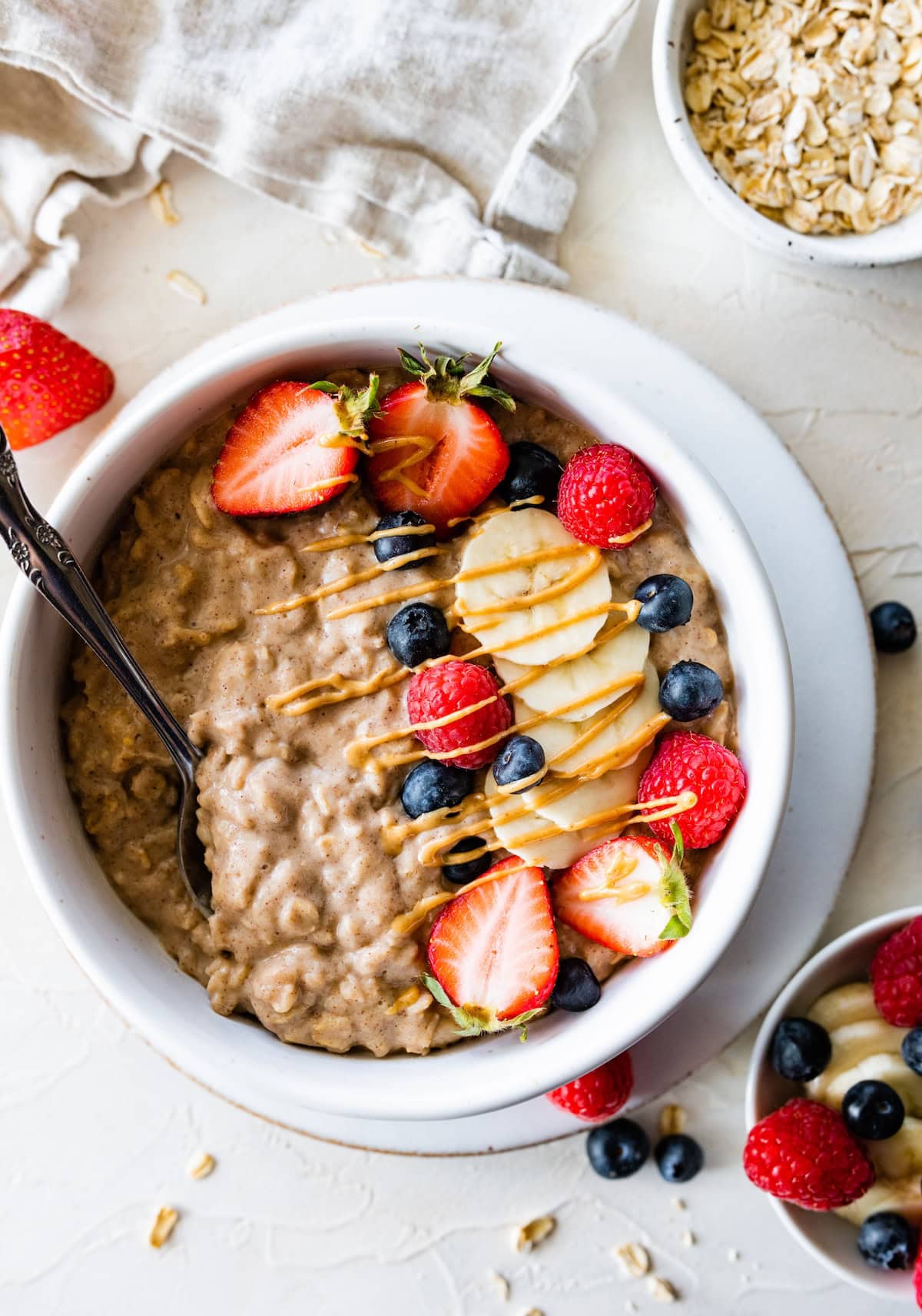 A bowl of protein oatmeal topped with fresh berries, banana slices, and a drizzle of nut butter.